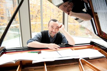 Jon Kimura Parker seen through the lid of an open piano leaning over sheet music splayed across the piano strings