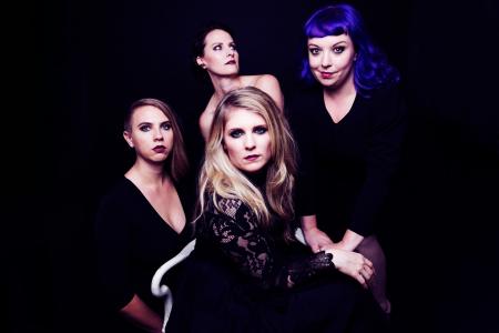 Quince vocal ensemble: 4 women in black, with a black background, crowd close to the camera