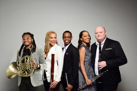 A group of musicians, holding their instruments, smiling.