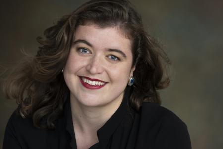 A headshot of a smiling brunette woman