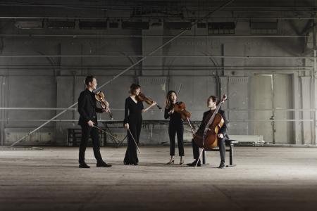 A string quartet in a candid moment, holding their instruments.