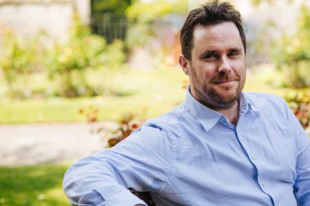 A headshot of a man in a blue shirt.