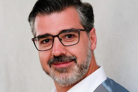 A headshot of a man in a vest. 