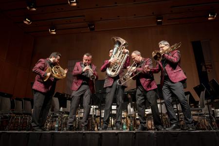 A group of five men in matching suits playing brass instruments.