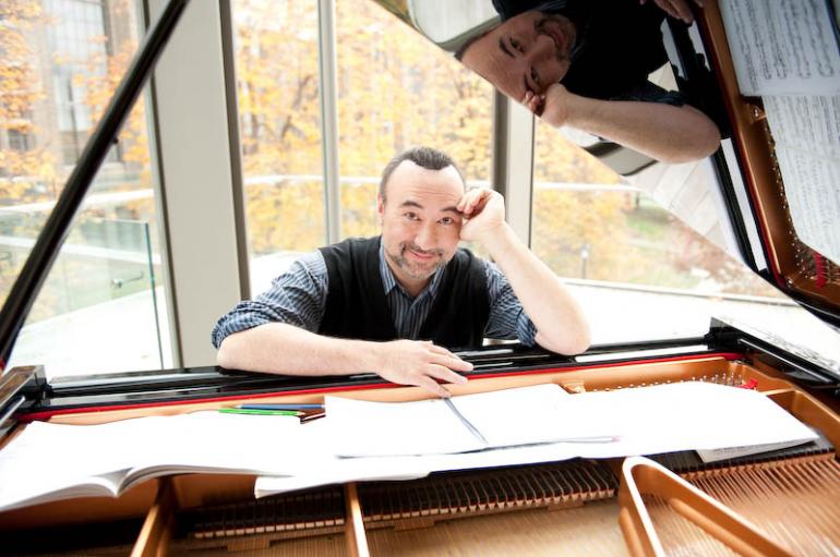Jon Kimura Parker seen through the lid of an open piano leaning over sheet music splayed across the piano strings