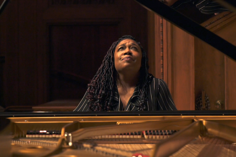 A woman sitting at a piano, looking upward
