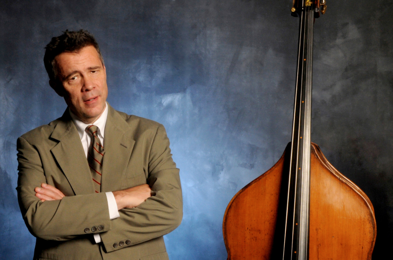A man in a suit standing to the left on an upright double bass.