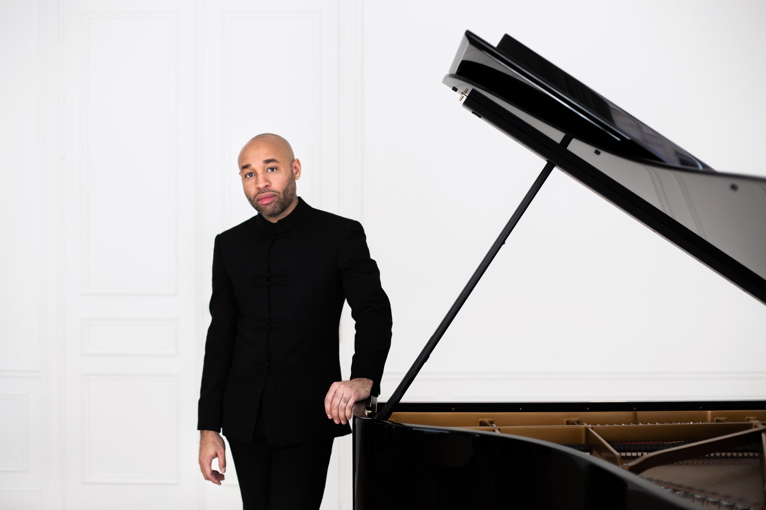 Aaron Diehl standing next to an open grand piano