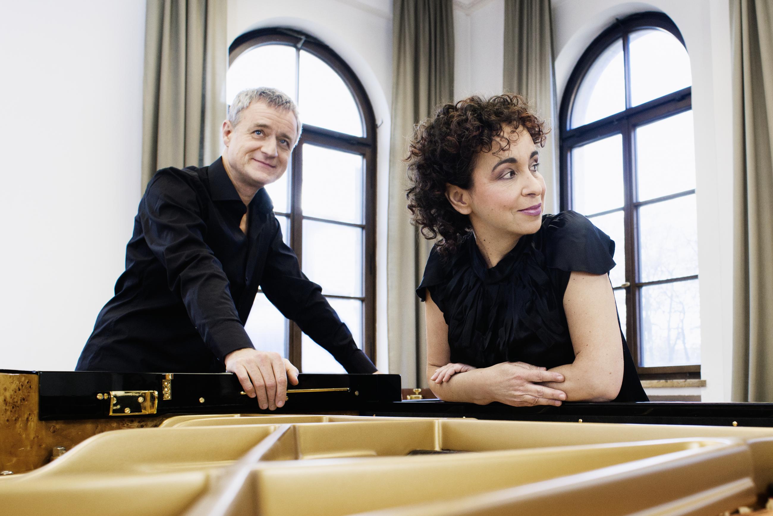 Duo Tal and Groethuysen leaning over an open grand piano