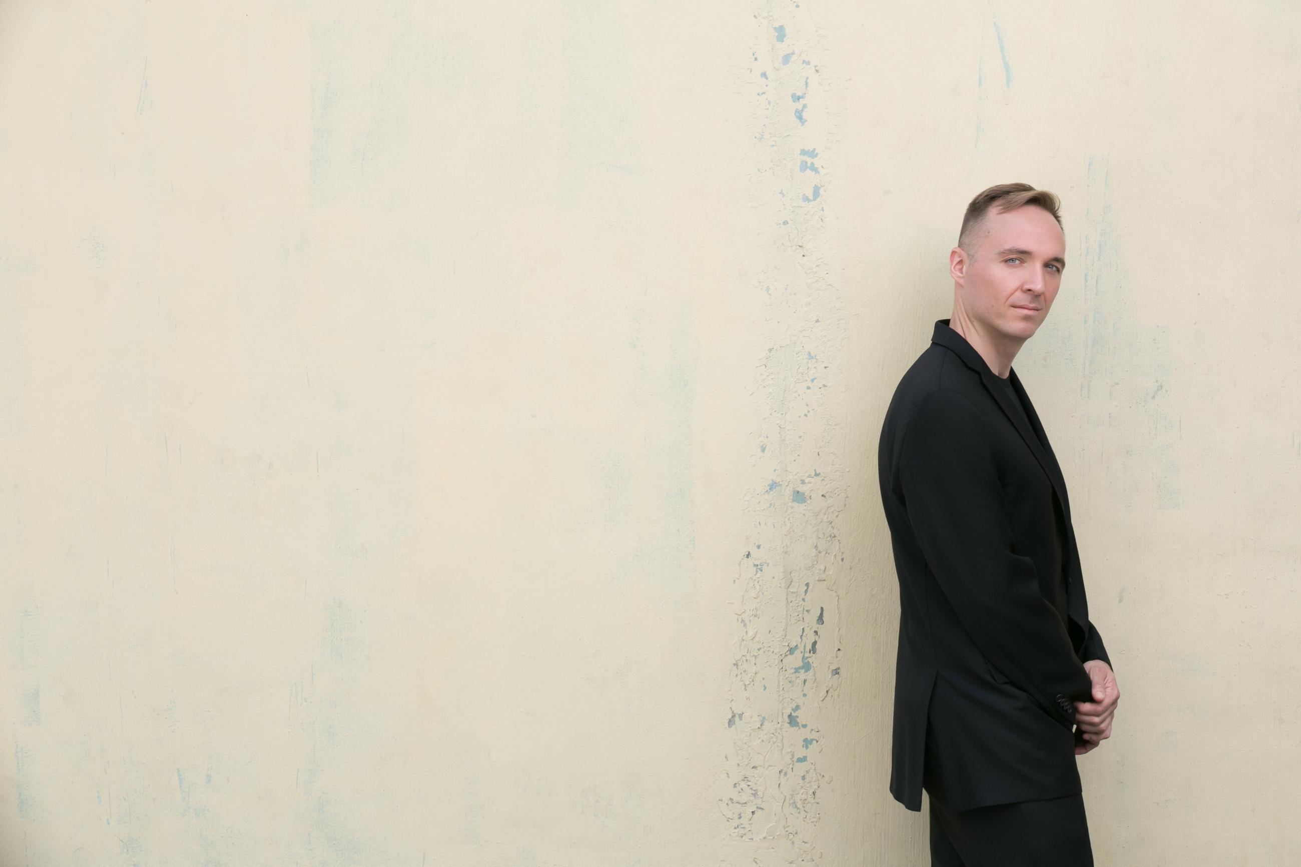 Austin Wulliman standing in front of a yellowish beige wall