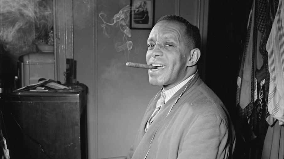 Willie "The Lion" Smith pictured at the piano with a cigar in his mouth