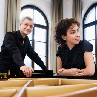 Pianists Yaara Tal and Andreas Groethuysen lean over an open piano