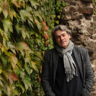 Gerold Huber next to an ivy covered stone wall