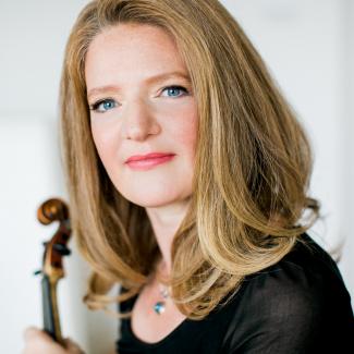 Rachel Podger looking into the camera closeup with the scroll of her violin just visible