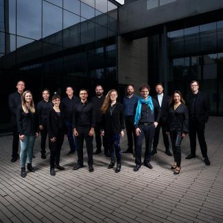 Contemporary Spotify image, featuring the members of the Grossman Ensemble dressed in black and blue standing in front of the Logan Center