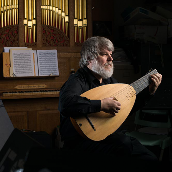 Paul O'Dette playing the lute in front of a pipe organ