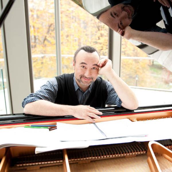 Jon Kimura Parker seen through the lid of an open piano leaning over sheet music splayed across the piano strings