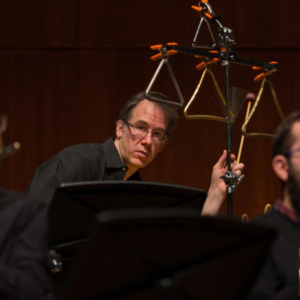 Closeup photo of three men, Tim Munro playing flute, Greg Beyer playing percussion, and Andrew Nogal playing oboe