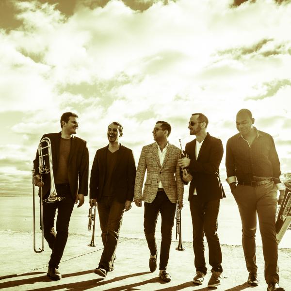 Sepia-toned photo of Axiom Brass with instruments walking outside