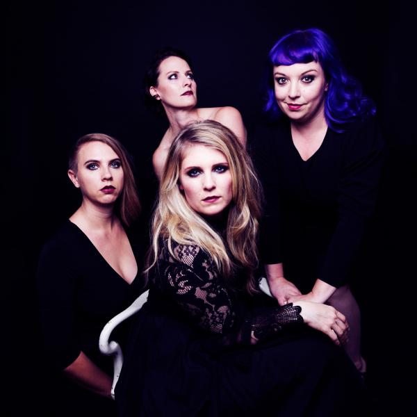 Quince vocal ensemble: 4 women in black, with a black background, crowd close to the camera