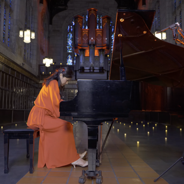 Eugenia Jeong performing on piano in Bond Chapel, surrounded by fake flickering candles