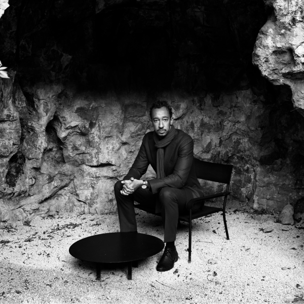A black and white photo of a man sitting alone in a cave.