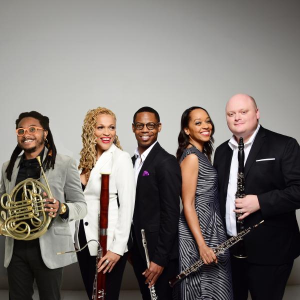 A group of musicians, holding their instruments, smiling.