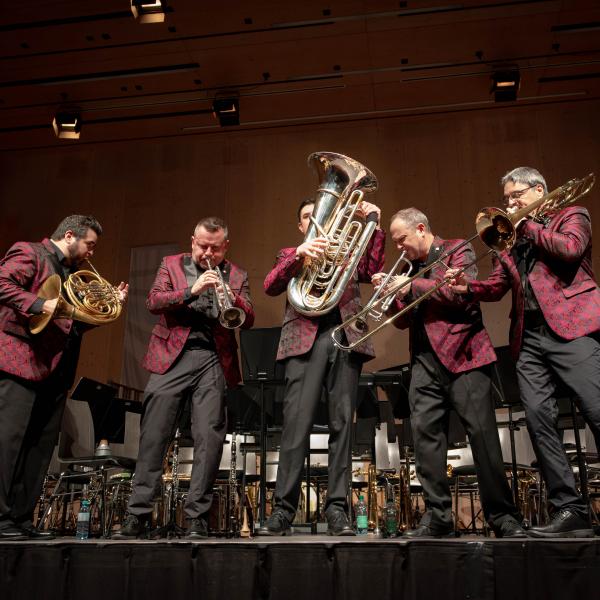 A group of five men in matching suits playing brass instruments.